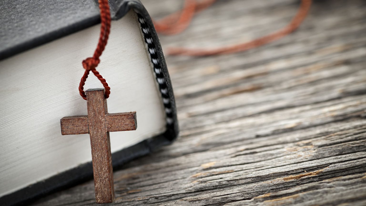 Small cross necklace/rosary on the edge of a Bible