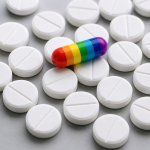 Rainbow-colored capsule resting atop scattered white scored tablets on a gray surface
