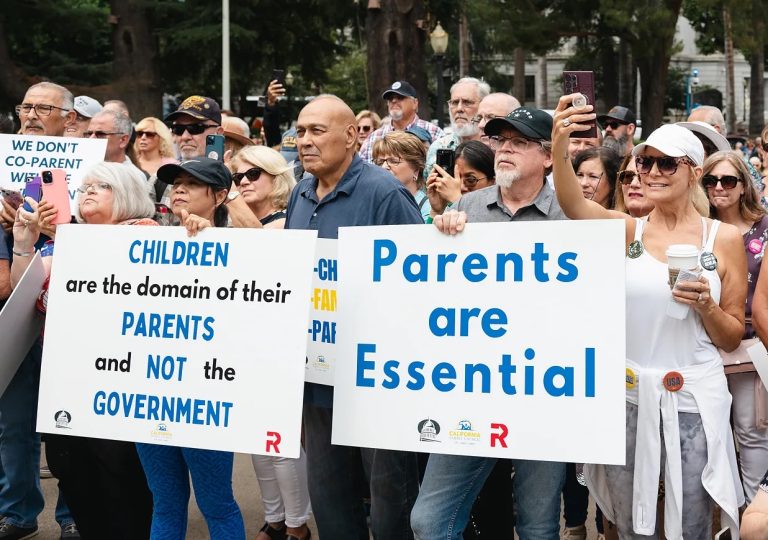 Crowd at outdoor rally holding signs reading Parents are Essential near a capitol building - California Family Council - California Family Council Crowd of protesters holding signs: 'Children are the domain of their parents and not the government' and 'Parents are Essential' at an outdoor rally, diverse participants visible with signs and phones raised.