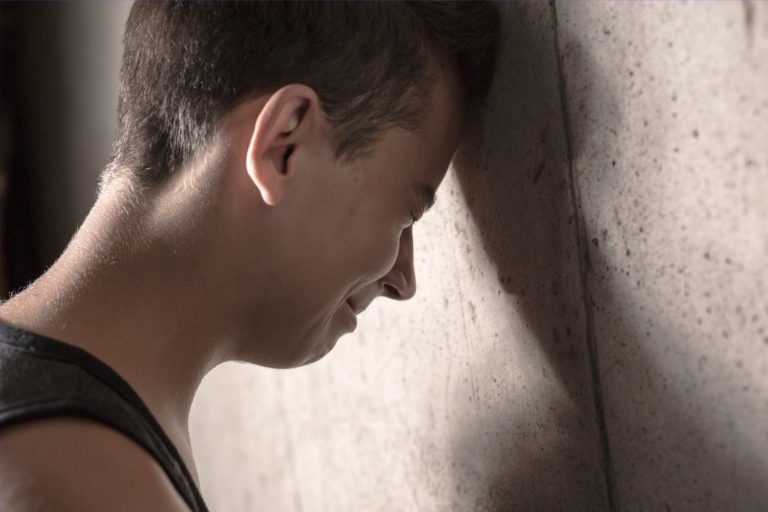 Sad boy - California Family Council - California Family Council Young man with his head resting against a textured wall, eyes closed in a moment of reflection or sadness.